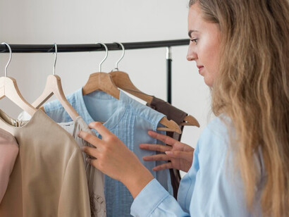 A woman examining sustainable fashion pieces, including garments crafted from organic cotton and recycled fabrics