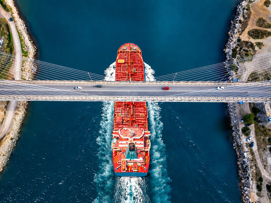 A large red tanker or chemical carrier passing beneath a modern cable-stayed bridge, Turkey