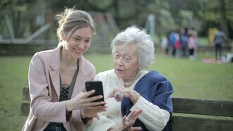 An elderly woman learning how to use technology from a young woman
