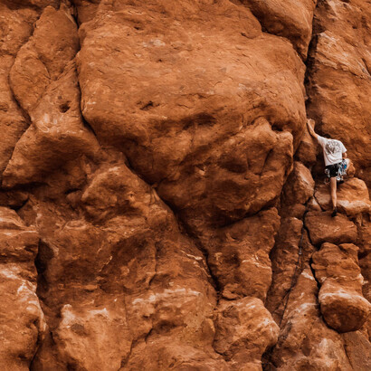 Homem escala uma grande rocha em busca de superar desafios e adversidades da vida 