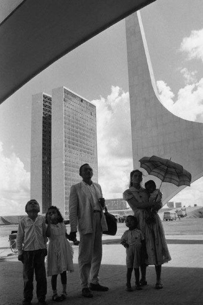 René Burri, ,A worker from Nordeste shows his family the new city on inauguration day. In the background: the National Congress building by Oscar Niemeyer. Brasilia, Brazil, 1960 © René Burri / Magnum Photos. Courtesy of Casa dei Tre Oci