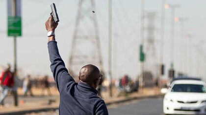 A South African in the middle of the road raising a gun to the sky crying out for justice