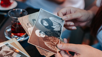 Mãos percorrem fotografias em caixa de recordações