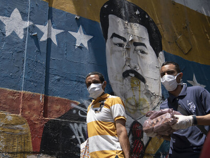 Ciudadanos caminan frente a un mural de Nicolás Maduro