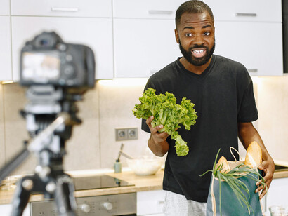 A male food vlogger presenting a lettuce while recording a cooking video