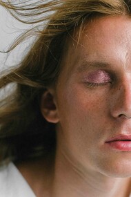 Modelo fecha os olhos para mostrar cores sintilantes em maquiagem nas pálpebras