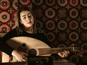 A woman immersed in the melodies of the oud, symbolising the preservation of Shaabi traditions across generations