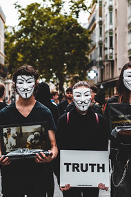 Four people wearing Guy Fawkes masks protest against disinformation, boldly demanding truth and transparency
