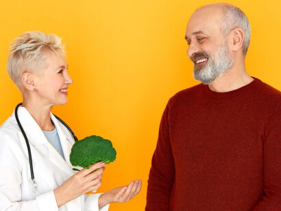 A successful middle-aged female doctor, stethoscope around her neck, shares an excited moment with her happy senior patient