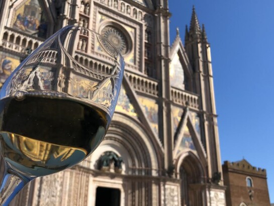 Un bicchiere di Orvieto DOC, sullo sfondo la facciata del Duomo di Orvieto, Italia. Foto di Isabella Ceccarelli