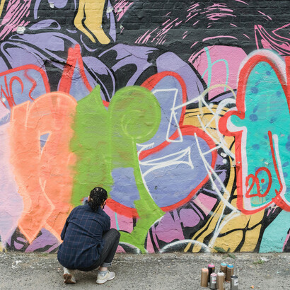 Grafitera interviniendo una pared de la ciudad. Las imágenes de arte figurativo o abstracto son conocidas como arte urbano