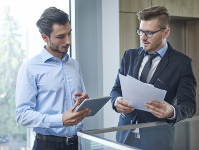 Two businessmen engrossed in paperwork, making decisions that ripple through the lives of others