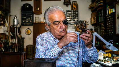 A watchmaker repairing an antique clock mechanism in his workshop