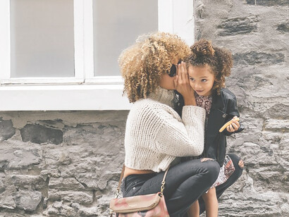 Amidst the lively street, a nurturing woman embraces her child with love and care
