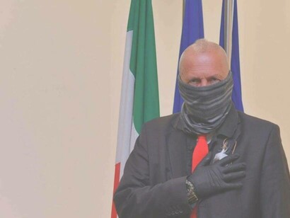 Sergio De Caprio hand on heart in front of the Italian flag