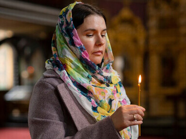 A woman praying in church, holding a candle, searching for inner strength, guidance, and spiritual wisdom