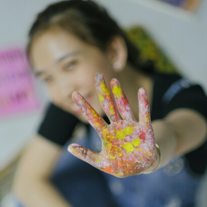 Felicidade ao mostrar uma mão cheia de cores que formou uma pétala de flor na palma da mão