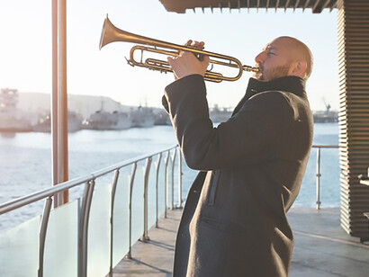 Experience the magic of Jazz Day with adult playing the trumpet by the seaside, blending soulful melodies with the rhythmic whispers of the sea
