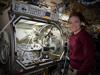 NASA astronaut and Expedition 73 Flight Engineer Nichole Ayers poses for a portrait while removing physics research hardware from the Microgravity Science Glovebox inside the Destiny laboratory module aboard the International Space Station. She was completing operations for the Ring Sheared Drop investigation, which may benefit pharmaceutical manufacturing and 3D printing in space