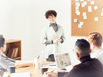 A digital marketing group strategizes together, with the woman giving her presentation and ideas
