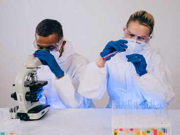 Researchers examining samples under a microscope in a laboratory, representing scientific efforts to advance melanoma treatment