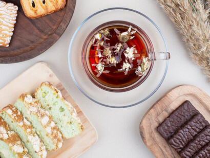 Delicious gluten-free zucchini cake slices paired with biscuits and a cup of tea, creating a delightful spread on a white surface