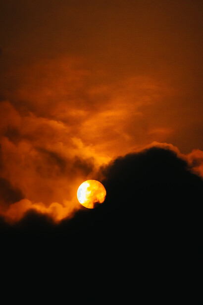Uma enorme bola vermelha no céu perfaz o encontro do sol com a lua