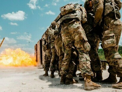 Troops advancing amid a battlefield explosion, symbolising the escalation of armed conflicts reshaping global politics