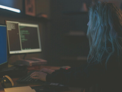 A woman immersed in her work, typing on a keyboard under the quiet glow of technology