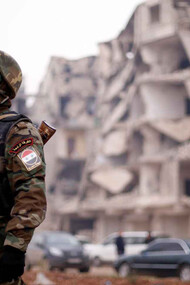 Un soldado de las fuerzas leales a Asad, cerca de edificios dañados en Alepo, Siria