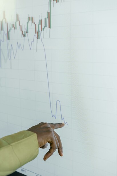 A person’s finger highlights data on a screen displaying stock market performance