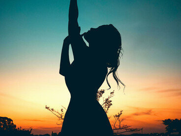 A lone silhouette beneath a crescent moon gazes into a star-filled sky, illuminated by a softly glowing path