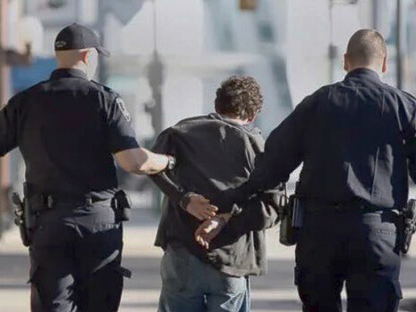 A young boy being arrested by the police in the middle of the day on the streets
