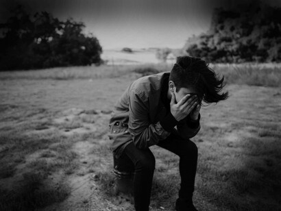 A man covering his eyes which are filled with sadness as he hopes to regain his happiness