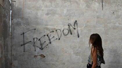 A woman stood in front of graffiti on a wall. Social justice and peace need to be central topics for all governments and international institutions