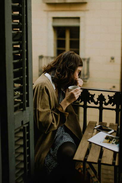 Joven viendo hacia la calle mientras toma café. Las ventanas de los bares son el lugar indicado para balconear