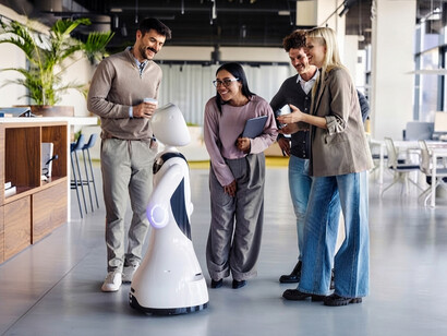 A team of business professionals works alongside an AI robot in a modern office