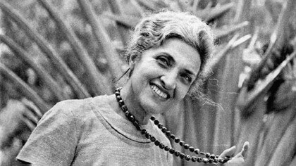 A autora Cecília Meireles sorrindo enquanto segura um colar de pedras 