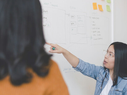 A poised girl stands confidently in front of a whiteboard, captivating her audience as she passionately discusses the power of influencer marketing, unveiling strategies and success stories that showcase the profound impact influencers can have on brand awareness and customer engagement