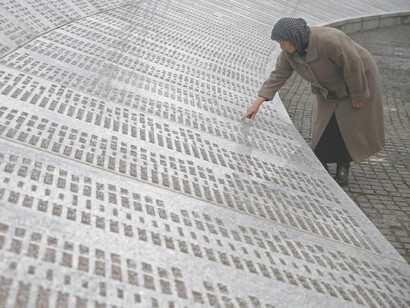 Mujer señala el nombre de un familiar entre el listado de las víctimas en el Monumento del Genocidio de Srebrenica