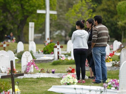 Una familia visita un cementerio por la festividad de Todos los Santos