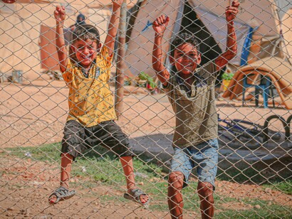 Children smiling behind fence