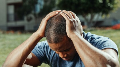Homem pensa com a cabeça entre as mãos