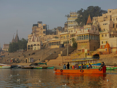 A group of boats peacefully floats on the serene waters near Golghar, Bazardiha, Maheshpur in Varanasi, Uttar Pradesh, India, showcasing the area's natural beauty