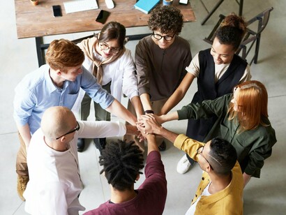 O círculo formado pelas mãos representa união e confiança entre colegas. Relações saudáveis no ambiente corporativo fortalecem equipes e resultados