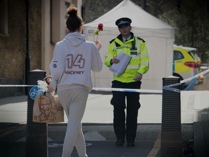 A police officer addressing the concerns of a relative to the victim of a recent crime in London, England