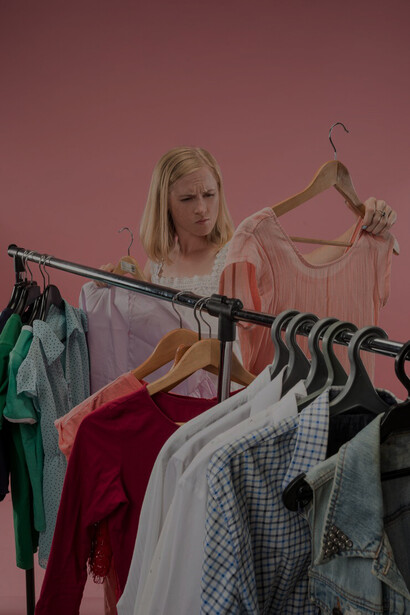 A frustrated woman choosing between dresses, feeling overwhelmed by the options