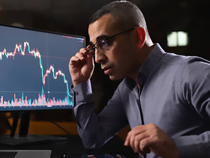 Fatigued individual tracking stock market exchange on laptop late into the night
