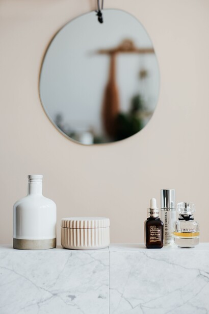 Skin care products on a counter underneath a mirror
