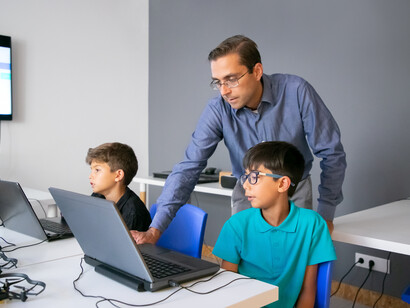 Un insegnante osserva il lavoro di uno studente al computer 